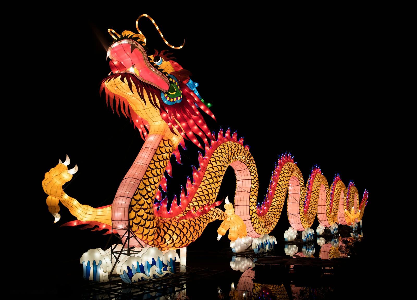 Giant Chinese dragon lantern glowing at night festival waterfront