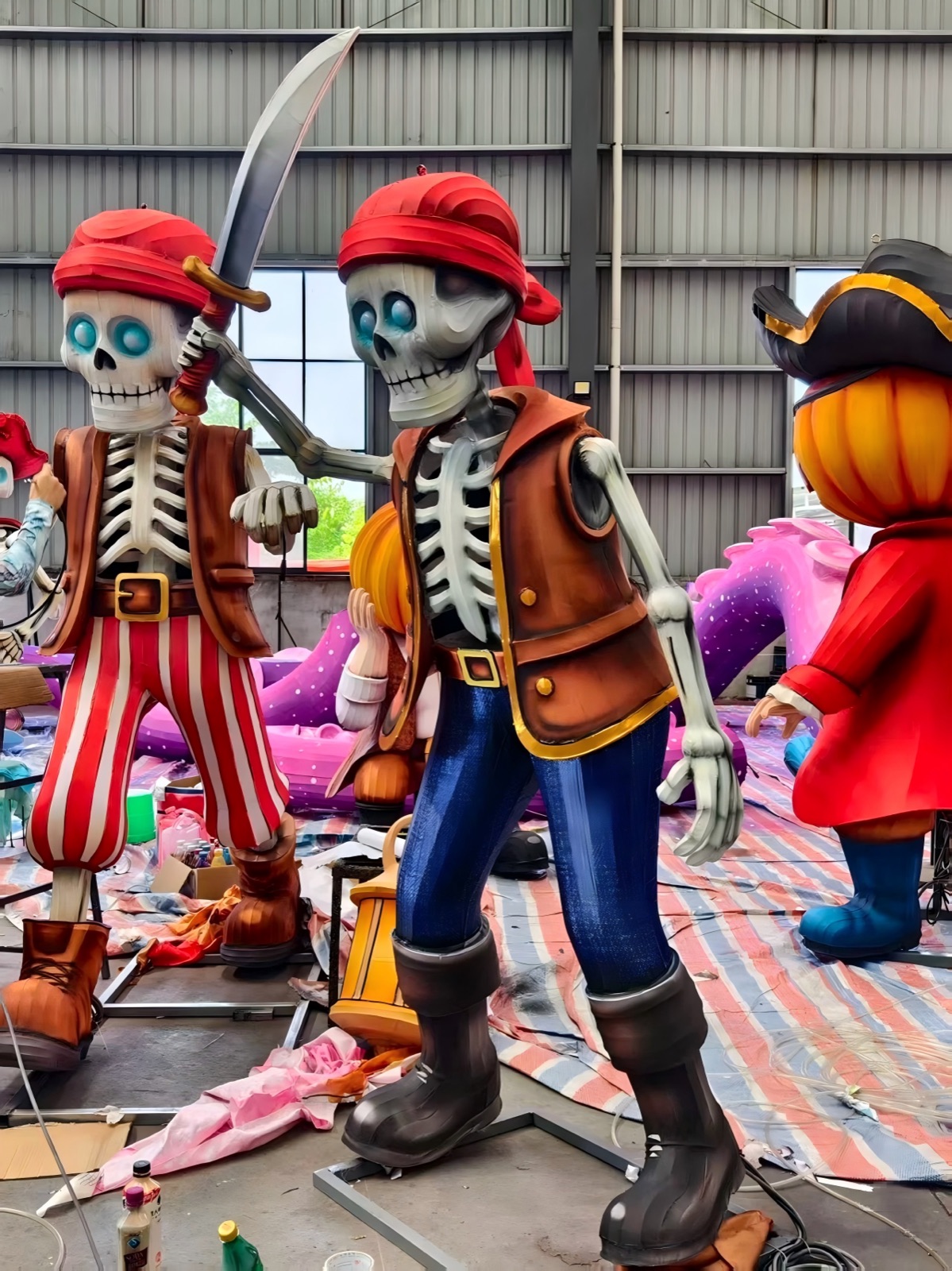 Two pumpkin-headed pirate lantern figures taking shape side by side in the workshop